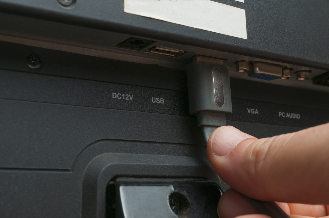 Someone plugging a USB into the back of a TV